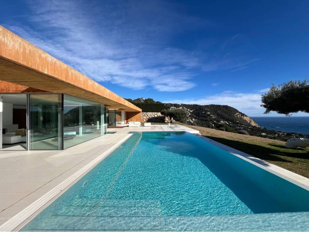 Amplia piscina junto a los grandes ventanales de un chalet